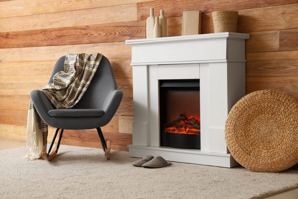 A stock image of an electric fireplace centerpiece next to a gray chair.