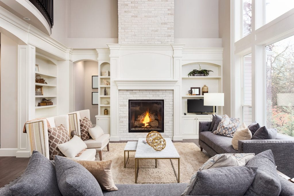 Stock image of a well-decorated room with a fireplace with a white surround.